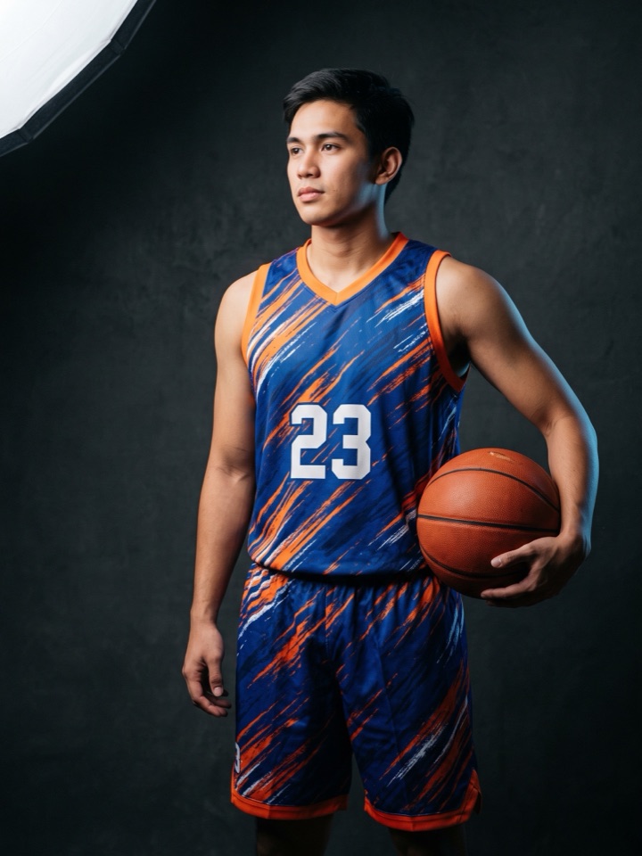 Player in a blue and orange sublimated basketball kit holding a ball